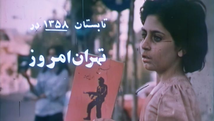 Film still from THE NEWBORNS: A girl holds up a picture of a man with a rifle.