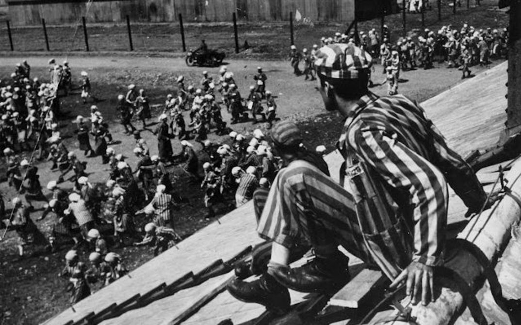 Filmstill aus THE END OF OUR WORLD: Eine Szene in einem Konzentrationslager, ein Häftling sitzt auf dem Dach einer Barracke.