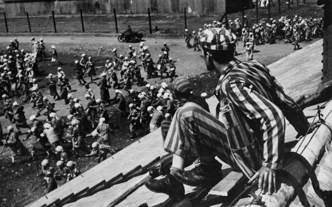 Film still from THE END OF OUR WORLD: A scene in a concentration camp, a prisoner sits on the roof of a barrack.