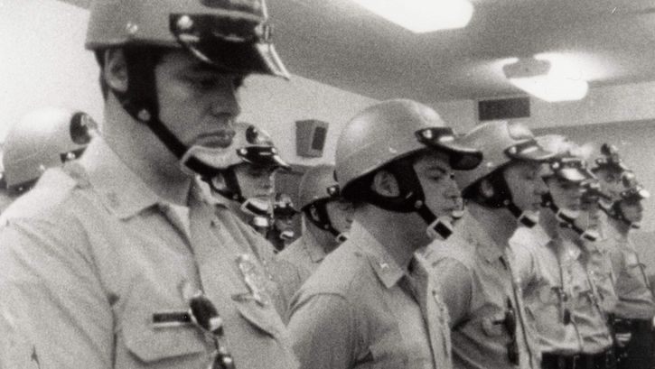 Film still from LAW AND ORDER. Police officers standing in a room.