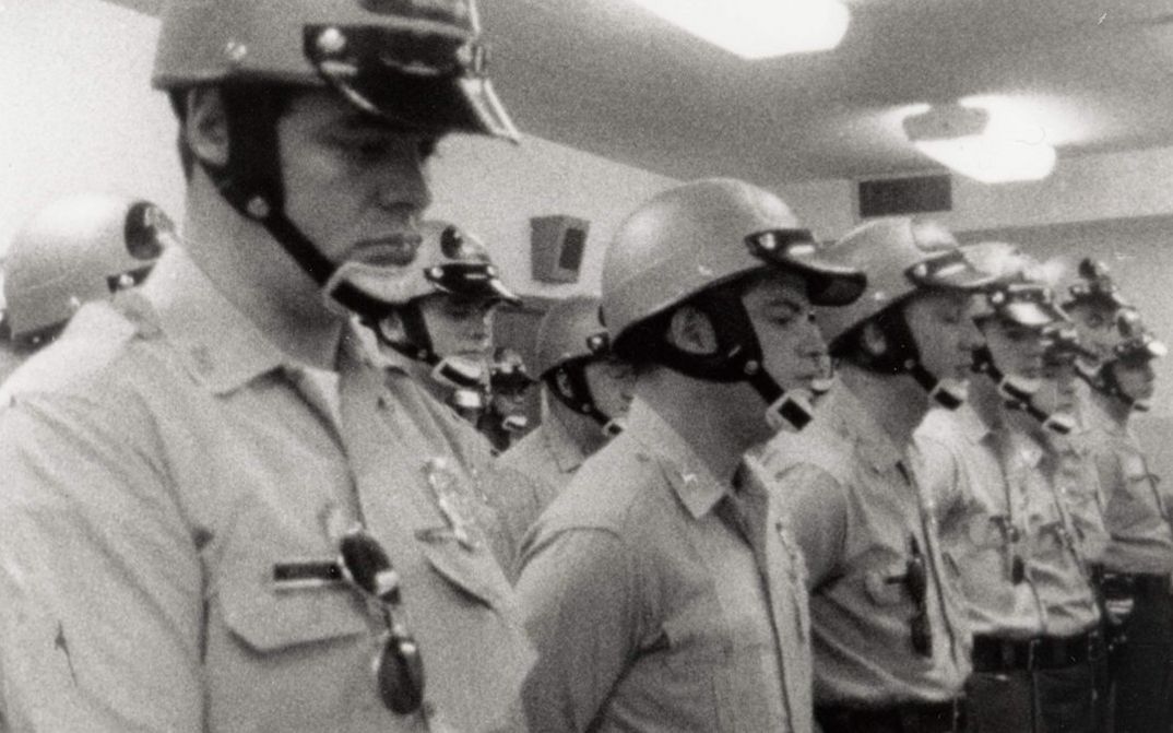 Filmstill aus LAW AND ORDER. Polizisten mit Helm stehen aufgereiht in einem Raum.