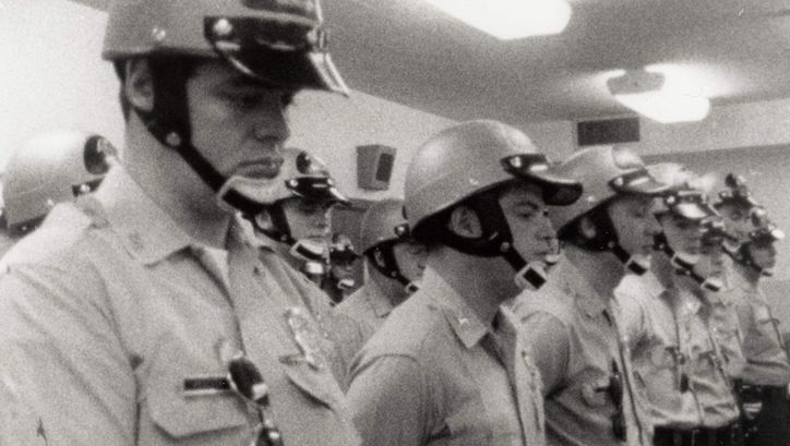 Filmstill aus LAW AND ORDER. Polizisten mit Helm stehen aufgereiht in einem Raum.
