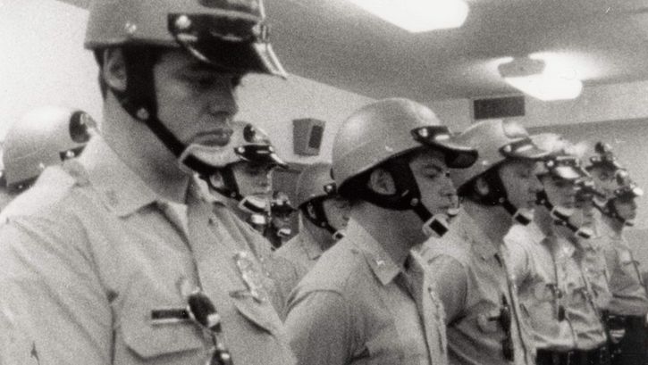 Film still from LAW AND ORDER. Police officers standing in a room.