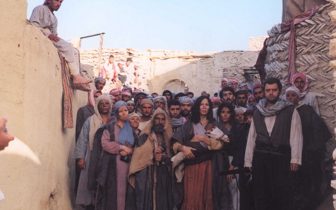 Filmstill aus THE GATE OF SUN: Dicht gedrängt steht eine Gruppe von Menschen auf einer Gasse zwischen Häusern und blicken ins Off.