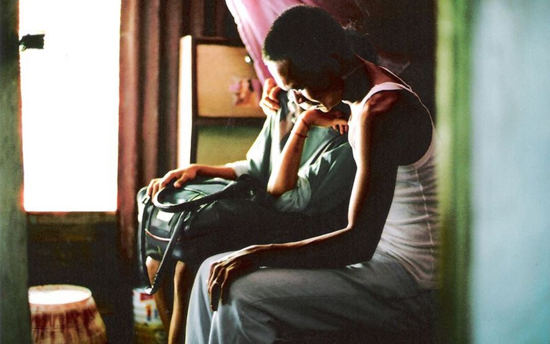 Film still from NO DAY OFF: Behind a door you can see two people sitting together.