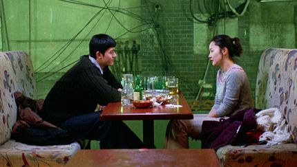 Film still from TALE OF CINEMA: In a pub, a man and a woman sit across from each other at a table full of glasses.