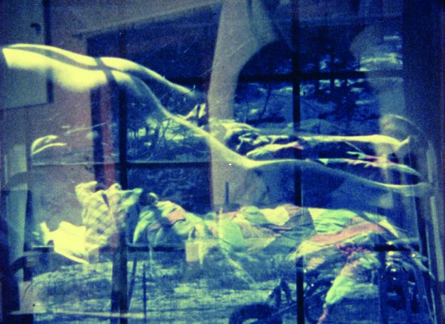 Film still from AN AVANT-GARDE HOME MOVIE: You see a double exposure of a snowy landscape and a naked body in a bed.
