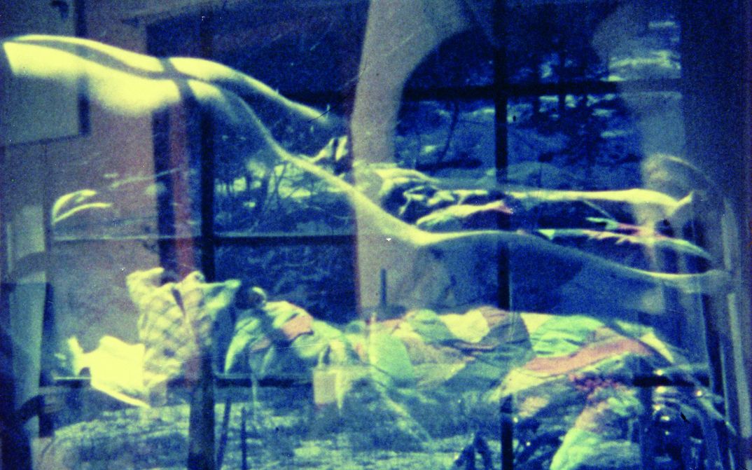 Film still from AN AVANT-GARDE HOME MOVIE: You see a double exposure of a snowy landscape and a naked body in a bed.