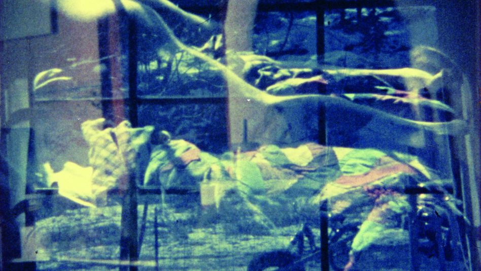 Filmstill aus AN AVANT-GARDE HOME MOVIE: Man sieht eine Doppelbelichtung aus einer Schneelandschaft und einem nackten Körper in einem Bett.