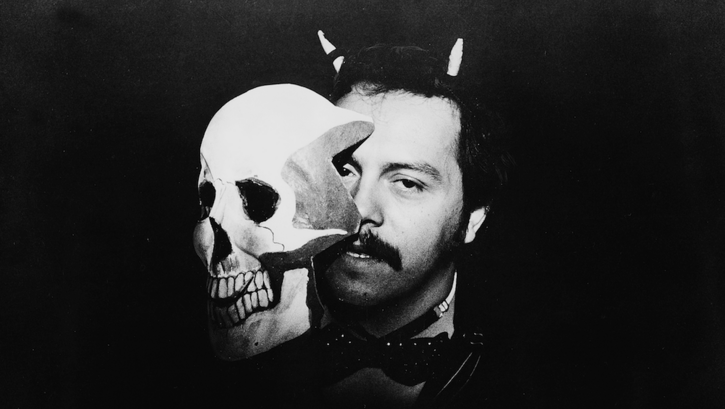 Filmstill aus BLONDER TANGO: Ein Mann hält eine Totenkopf-Maske vor sein Gesicht.