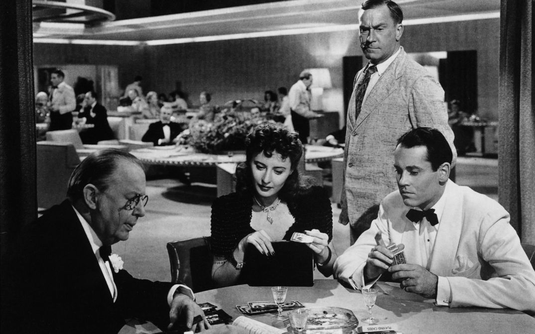 Filmstill aus THE LADY EVE: Ein Frau und zwei Männer, alle elegant gekleidet, spielen Karten.