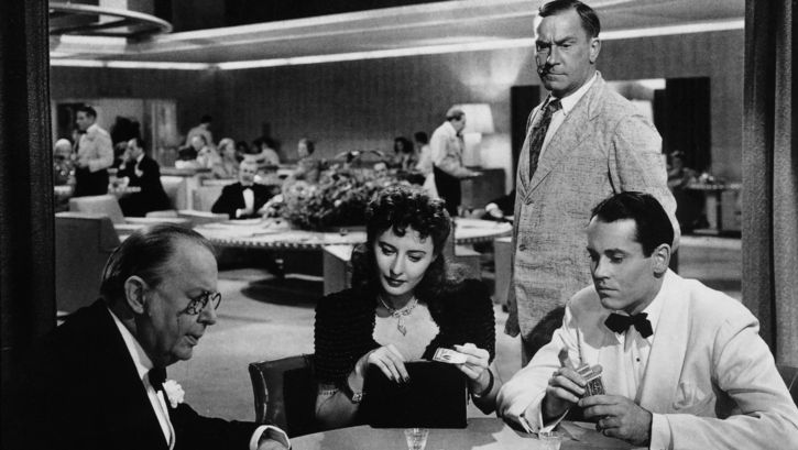 Filmstill aus THE LADY EVE: Ein Frau und zwei Männer, alle elegant gekleidet, spielen Karten.