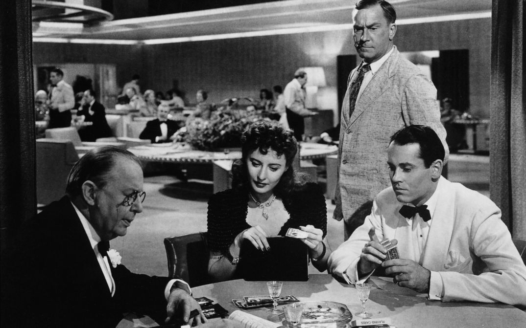 Filmstill aus THE LADY EVE: Ein Frau und zwei Männer, alle elegant gekleidet, spielen Karten.