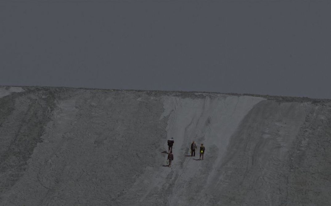 Film still from Zhou Tao’s film “The Periphery of the Base”. Four people climb what seems to be a clay hill.