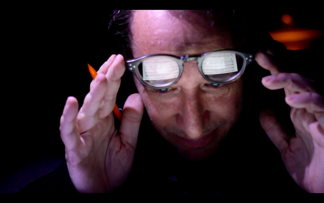 Film still from ZORN. Close-up of John Zorn, musical notes reflected in his glasses.