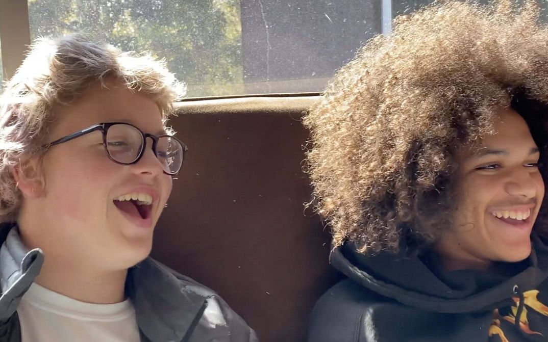 Film still from TEENAGER EMOTIONS: Two teenagers are sitting on a sofa laughing.