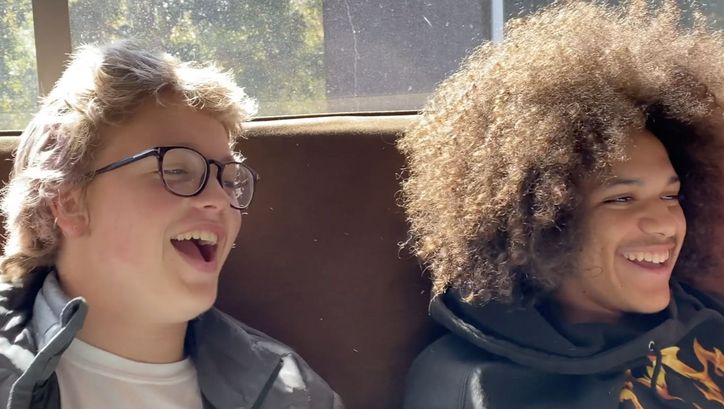 Film still from TEENAGER EMOTIONS: Two teenagers are sitting on a sofa laughing.