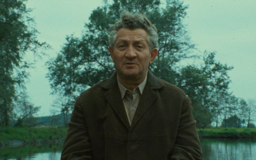 Filmstill aus SHOAH: Ein älterer Mann im Gespräch, hinter ihm sind Wasser und Bäume zu sehen.