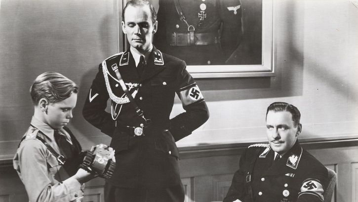 Filmstill aus TO BE OR NOT TO BE: Zwei Wehrmacht-Offiziere mit einem ebenfalls Uniform tragenden Jungen in einem Zimmer.