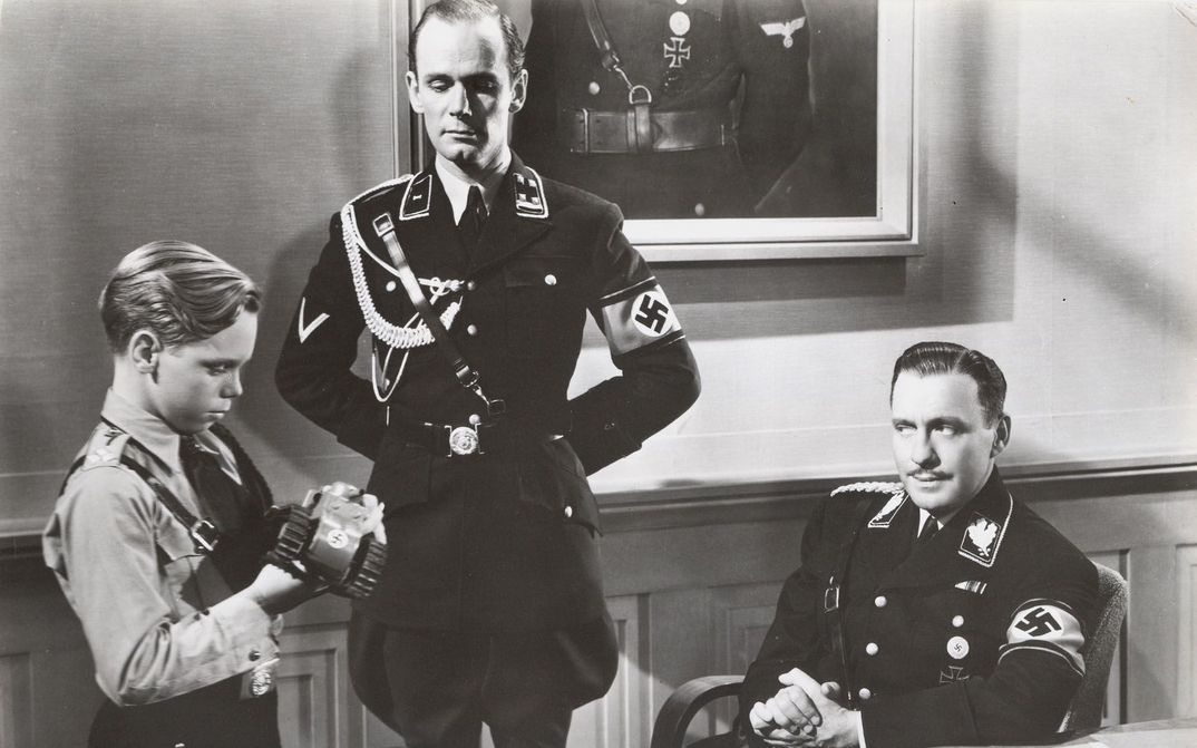 Film still from TO BE OR NOT TO BE: Two Wehrmacht officers with a boy also in uniform in a room.