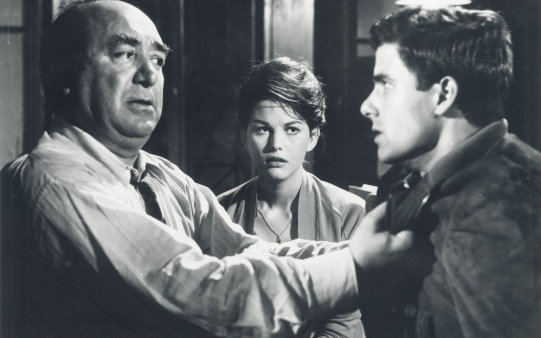 Film still from UN MALEDETTO IMBROGLIO: In the foreground are two men in an argument. A woman stands behind them and watches them.