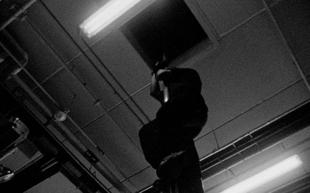 Filmstill from the Film "Fire Emergencies" by Kevin Jerome Everson. a man slides down a fire pole.