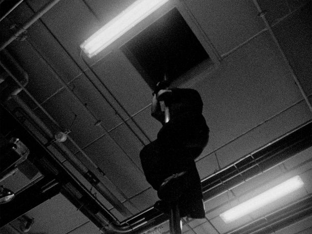 Filmstill from the Film "Fire Emergencies" by Kevin Jerome Everson.  a man slides down a fire pole.
