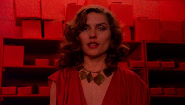 Filmstill from VIDEODROME: colour with a large geometric chain. The photo is in red colours.