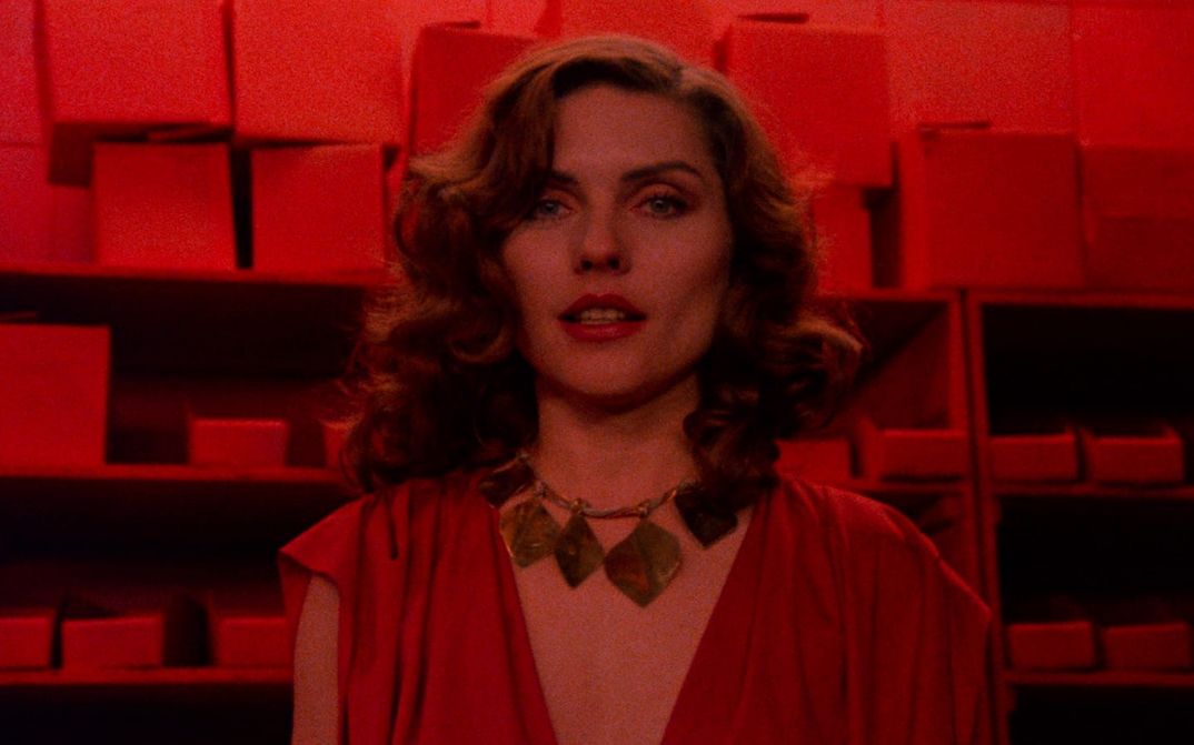 Filmstill from VIDEODROME: colour with a large geometric chain. The photo is in red colours.