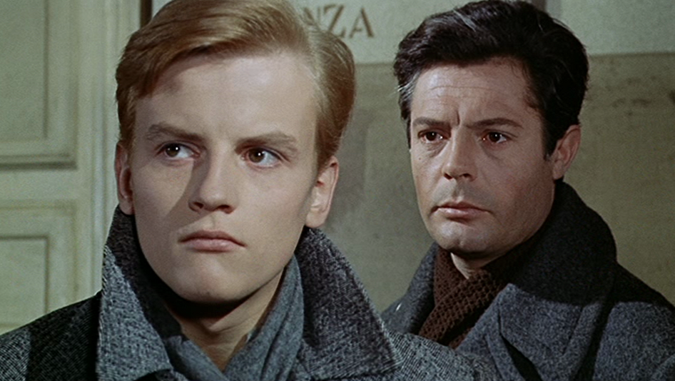 Filmstill aus CRONACA FAMILIARE. Zwei Männer in Wintermänteln stehen hintereinander, einer davon ist Marcello Mastroianni.