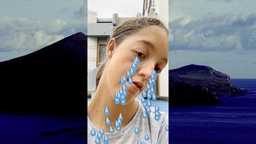 Still from the film "Super Natural". A vertical screenshot of a young woman with animated tears flowing from her eyes is layered over the image of an ocean island. 