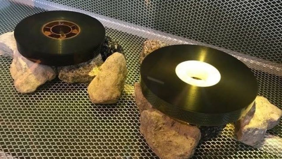 Two analog film reels are lying on stones.