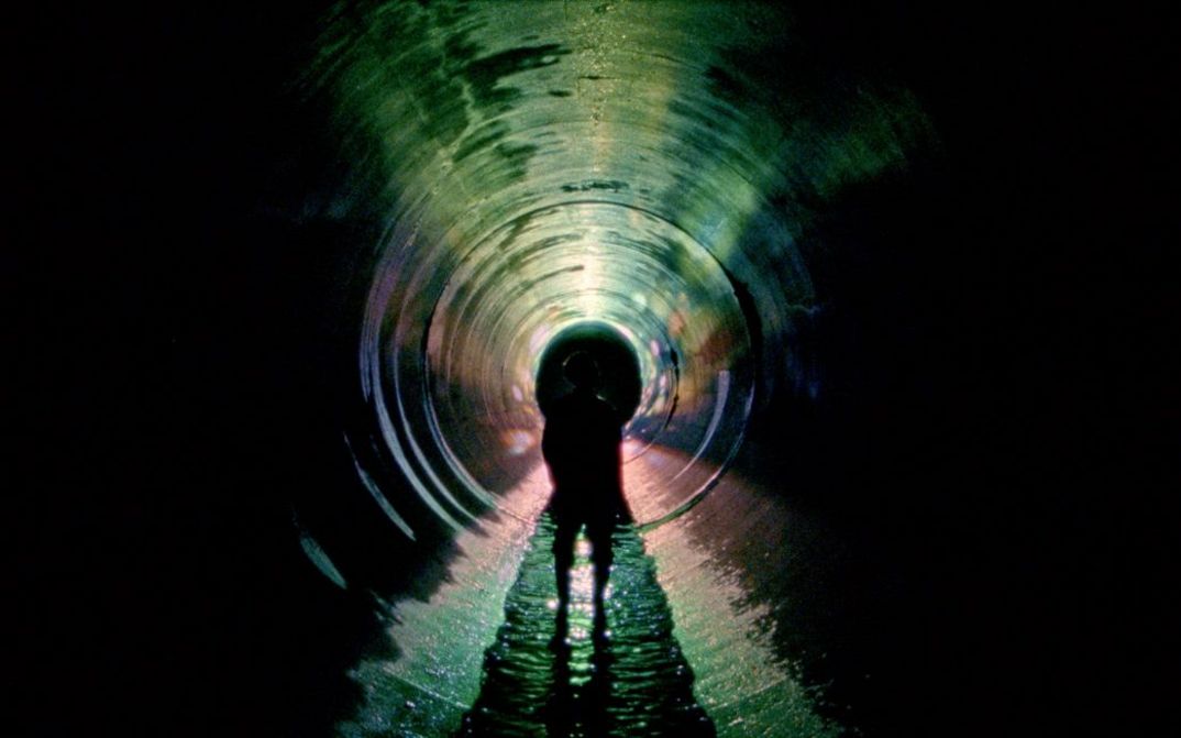 Filmstill aus UNDERGROUND von Kaori Oda. Das Bild zeigt die Umrisse eines Menschen in einem langen dunklen Tunnel.