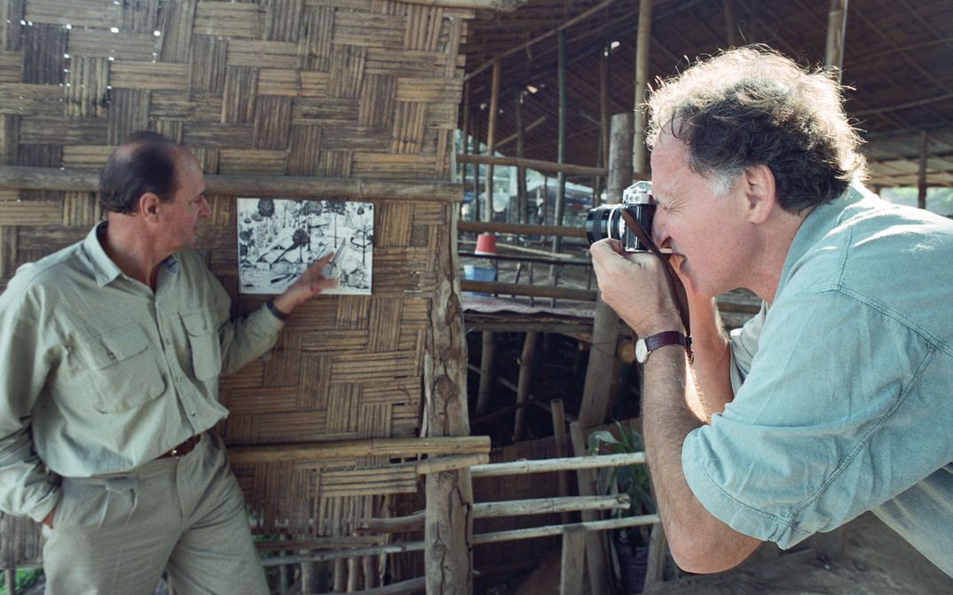 Szenenfoto aus LITTLE DIETER NEEDS TO FLY: Der Regisseur Werner Herzog fotografiert Dieter Dengler, der auf eine Fotografie deutet.