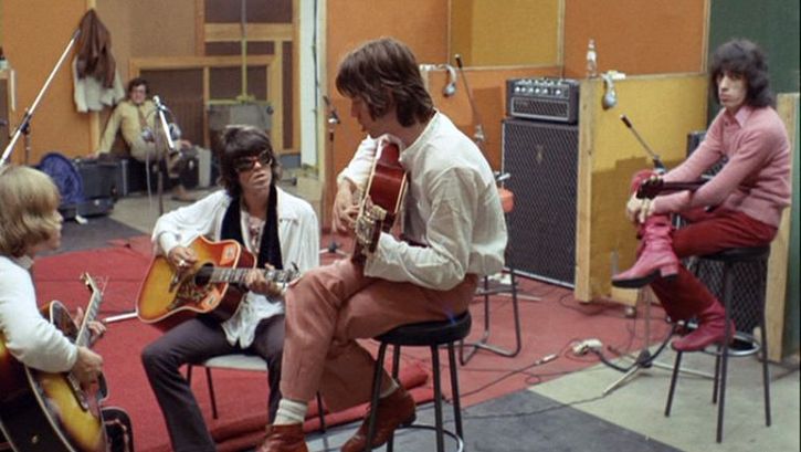 Film still from ONE PLUS ONE: The Rolling Stones making music in a recording studio.