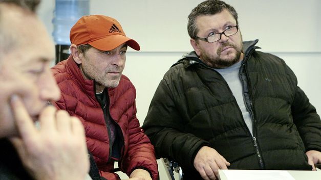 Still from the film "(For the Many – The Vienna Chamber of Labour)" by Constantin Wulff: Three men in an office room. They are listening to and looking at someone off camera.