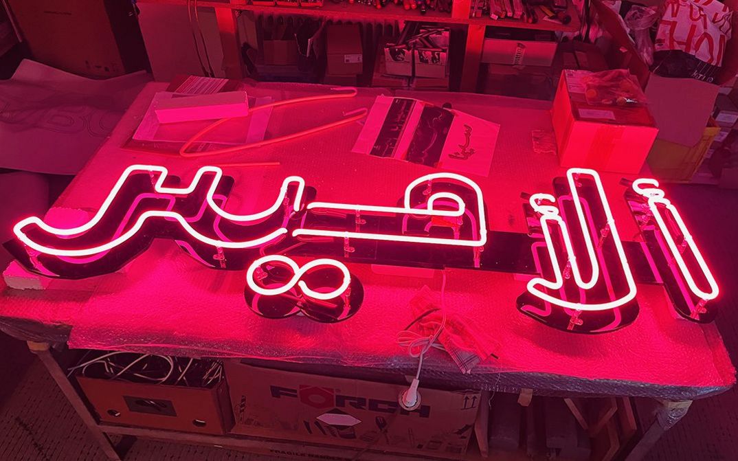 Still from the installation "The Cinema Project" by Siska. Red fluorescent tubes in the darkness form Arabic lettering.