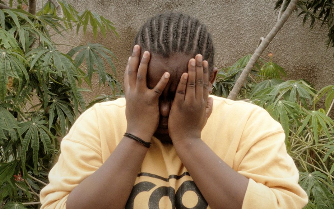 Still from the film "The Lighting" by Musquiqui Chihying. A person covers their face with their hands.