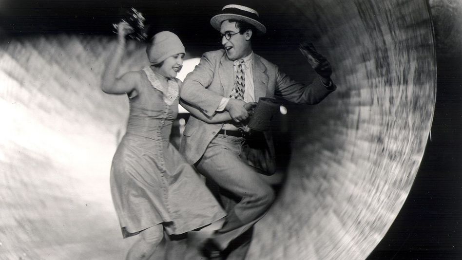 Filmstill aus SPEEDY von 1928: Ein Mann und eine Frau sind in einer Art Rohr in einem Vergüngungspark und lachen sich an.