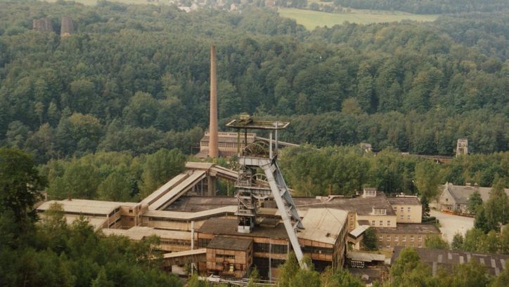 Filmstill aus DIE WISMUT: Die Anlage eines Bergbauunternehmens inmitten von Bäumen.