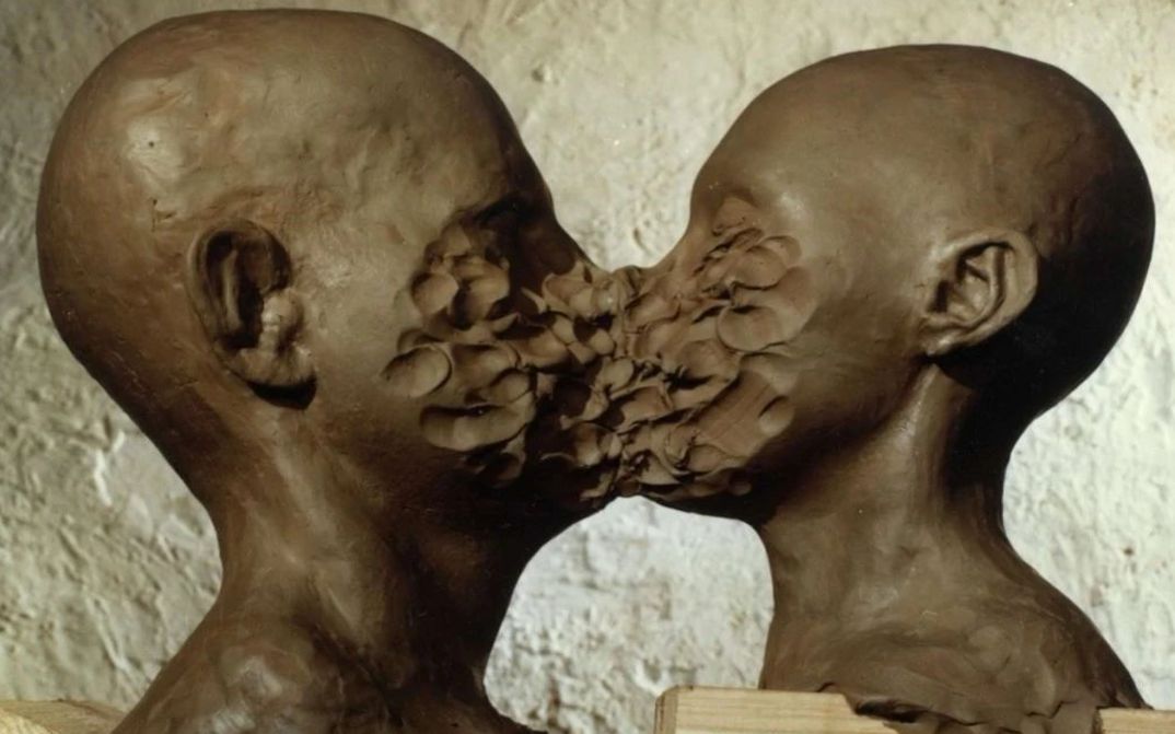 Filmstill aus DIMENSIONS OF DIALOGUE: Zwei aus Ton geformte Köpfe sind sich gegenüber, ihre Münder und Nasen sind miteinander verschmolzen.