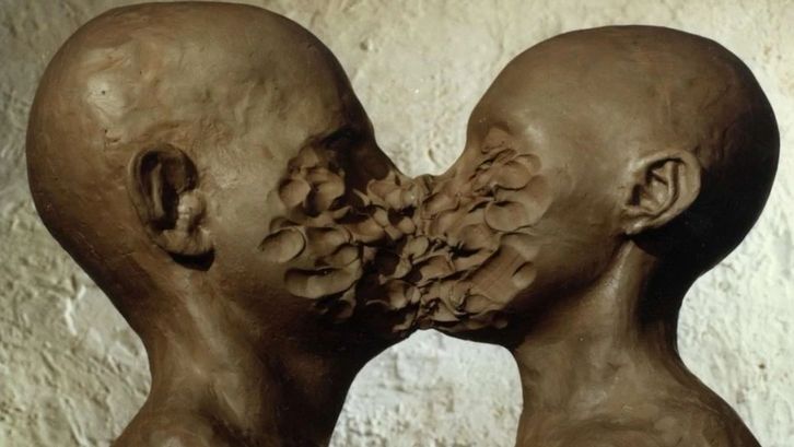 Filmstill aus DIMENSIONS OF DIALOGUE: Zwei aus Ton geformte Köpfe sind sich gegenüber, ihre Münder und Nasen sind miteinander verschmolzen.
