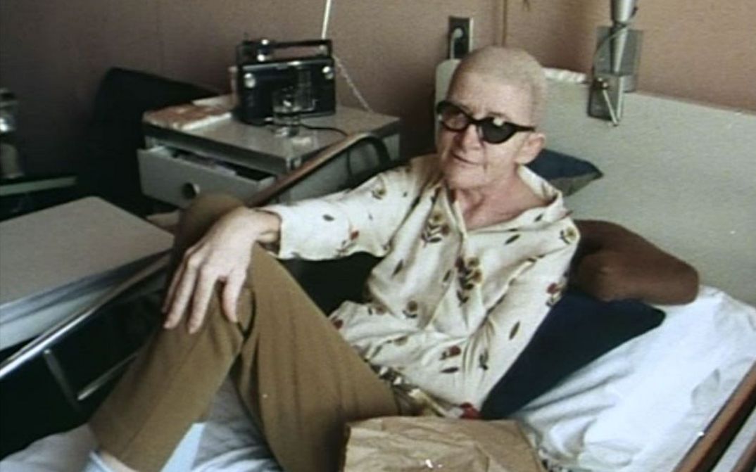 Filmstill aus DYING: Eine Person sitzt in einem Krankenhausbett.