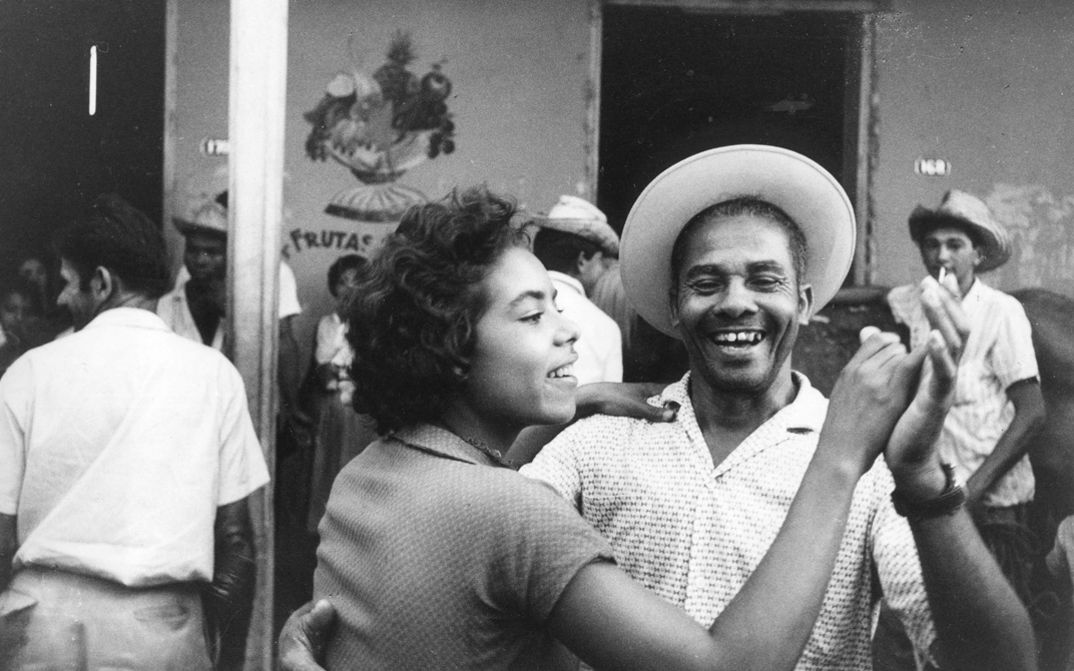 Film still from SALUT LES CUBAINS. A couple dancing and laughing.