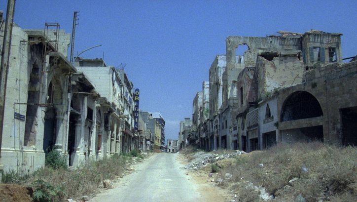Filmstill aus BEIRUT, THE ENCOUNTER. Eine leere Straße gesäumt von Häusern in Ruinen.