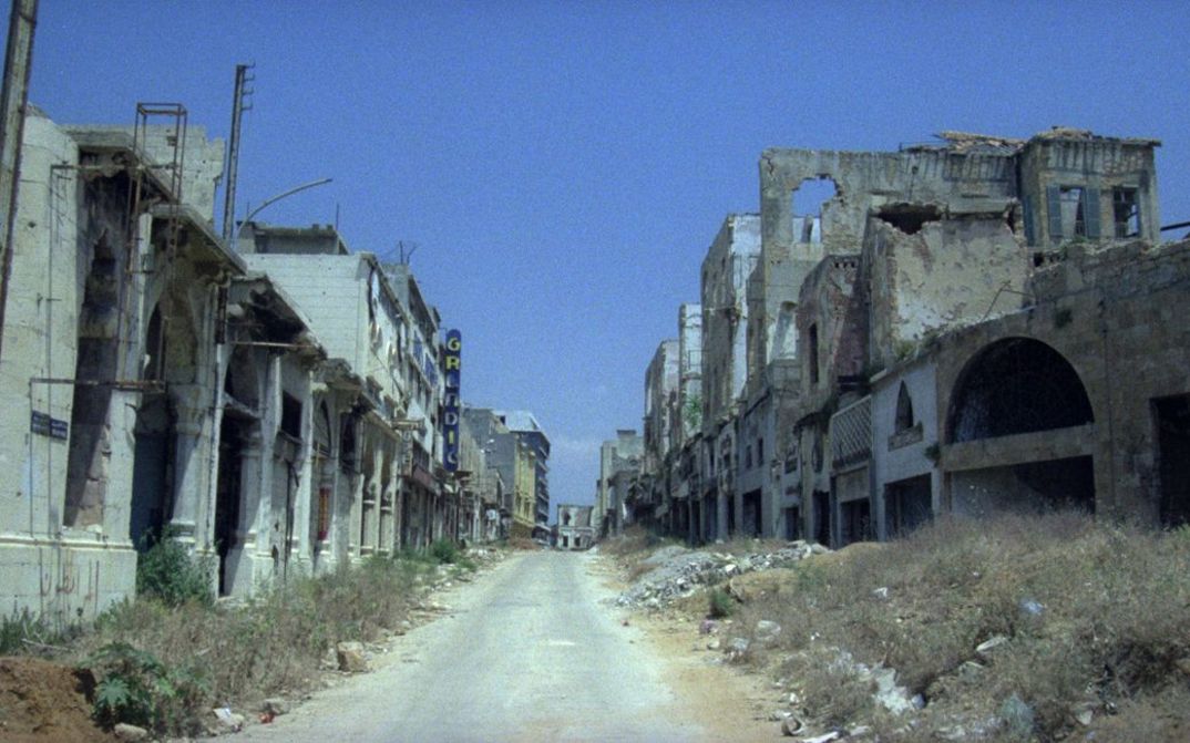 Filmstill aus BEIRUT, THE ENCOUNTER. Eine leere Straße gesäumt von Häusern in Ruinen.