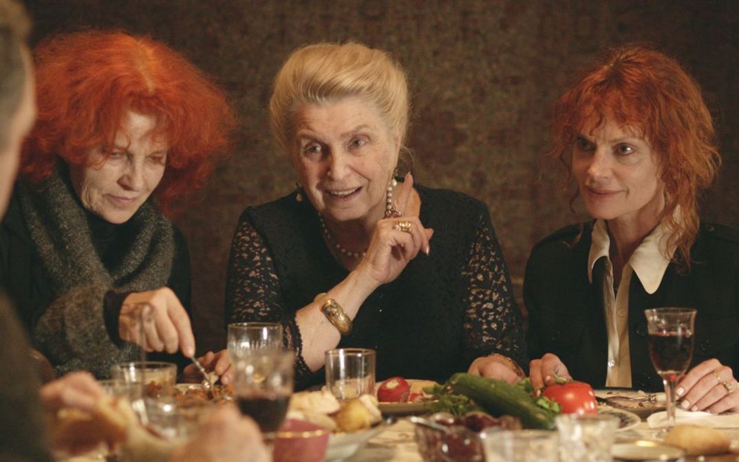 Filmstill aus THE GOLDEN THREAD. Drei Frauen sitzen an einem gedeckten Tisch.