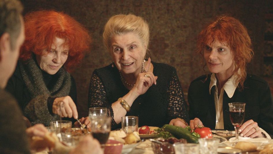 Filmstill aus THE GOLDEN THREAD. Drei Frauen sitzen an einem gedeckten Tisch.