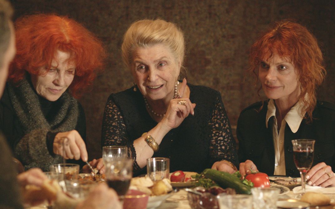 Filmstill aus THE GOLDEN THREAD. Drei Frauen sitzen an einem gedeckten Tisch.
