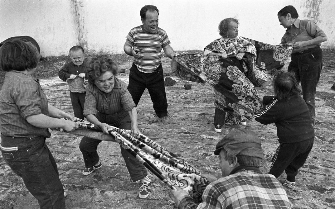 Film still from AUCH ZWERGE HABEN KLEIN ANGEFANGEN: A group of people of short stature pull on two large cloths.